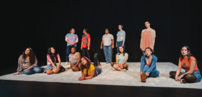 A group of women on a white carpet. Some are sitting on thefloor, a few are lying down, and others are standing